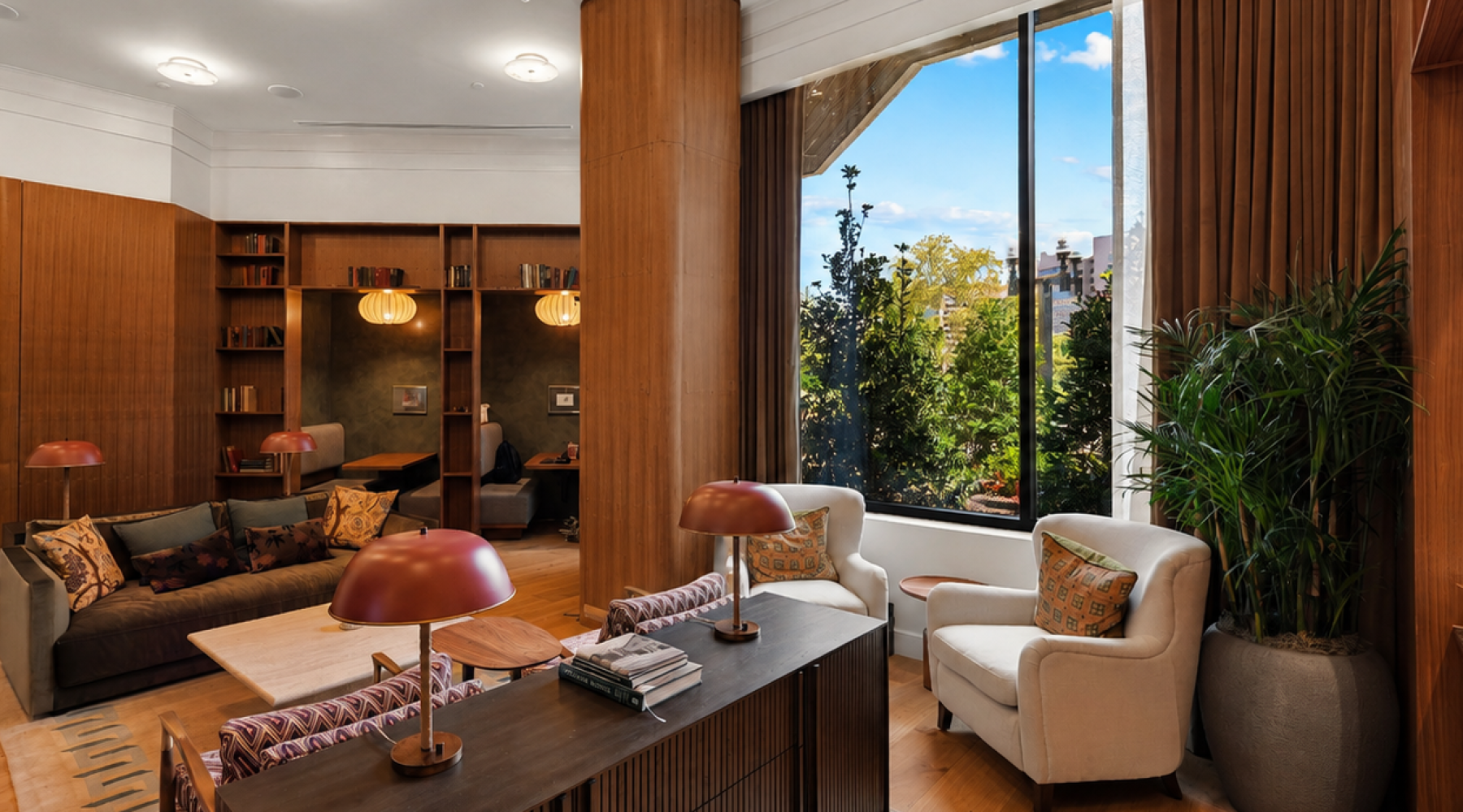 Cozy resident library area at Huxley featuring built-in bookshelves, comfortable seating, warm lighting, and floor-to-ceiling windows.