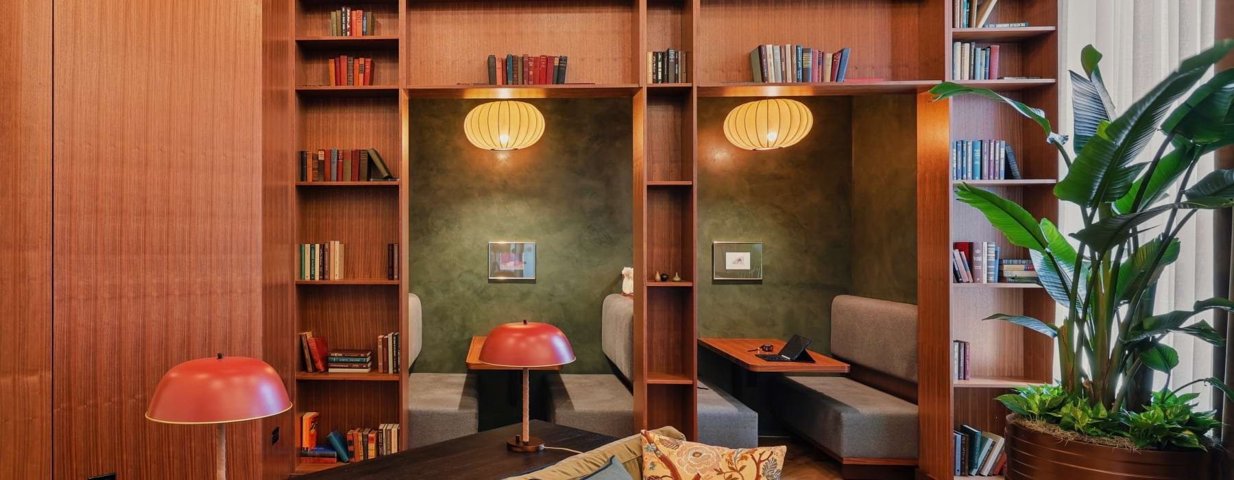 Co-working library lounge with built-in seating pods and wooden bookshelves at Huxley apartments in Arlington VA