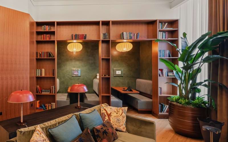 Co-working library lounge with built-in seating pods and wooden bookshelves at Huxley apartments in Arlington VA