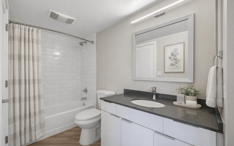 Modern apartment bathroom with white subway tile and vanity lighting at Huxley Apartments in National Landing, Arlington, VA